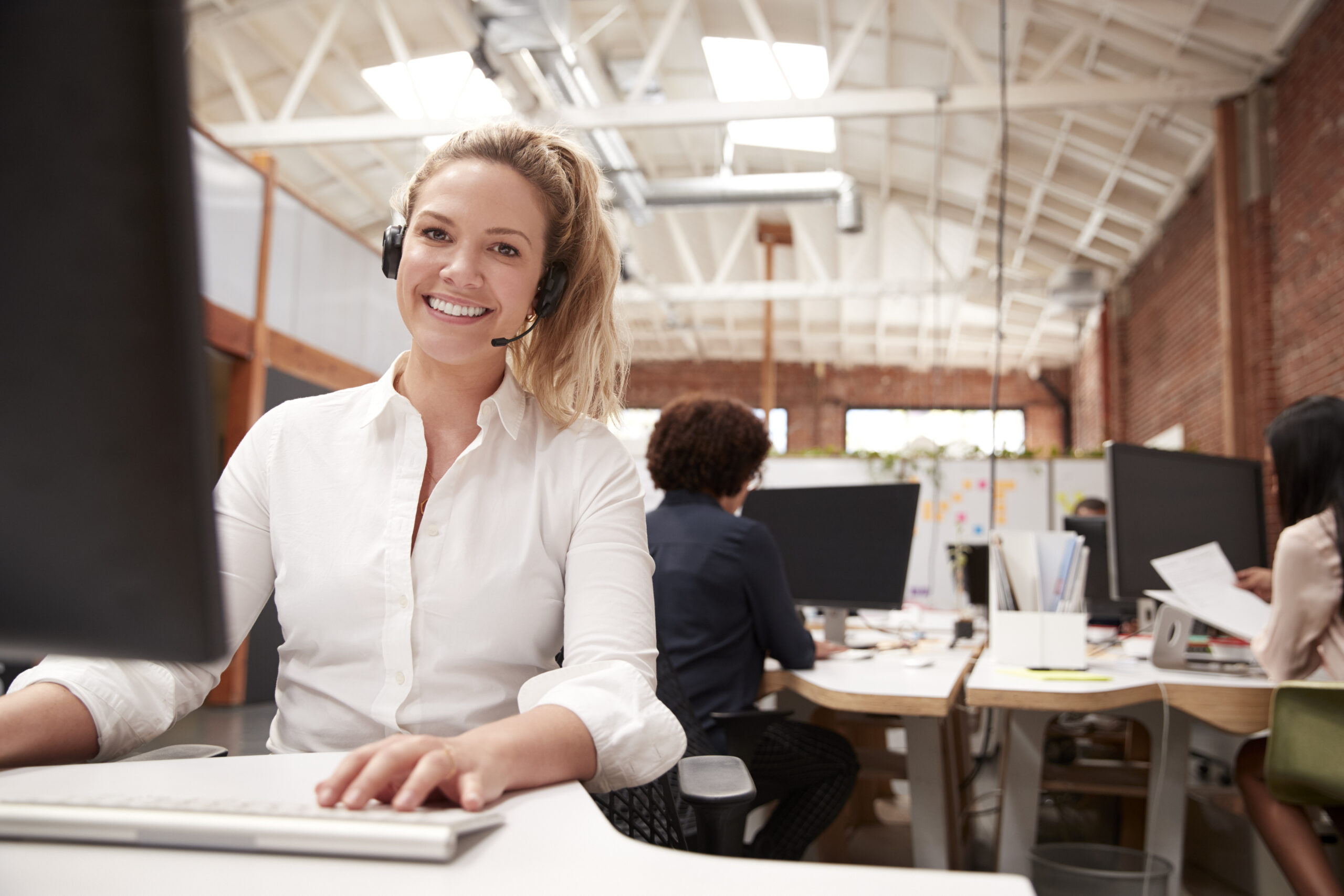 Portrait Of Female Customer Services Agent Working At Desk In Call Center Helpdesk Service Ticketsystem