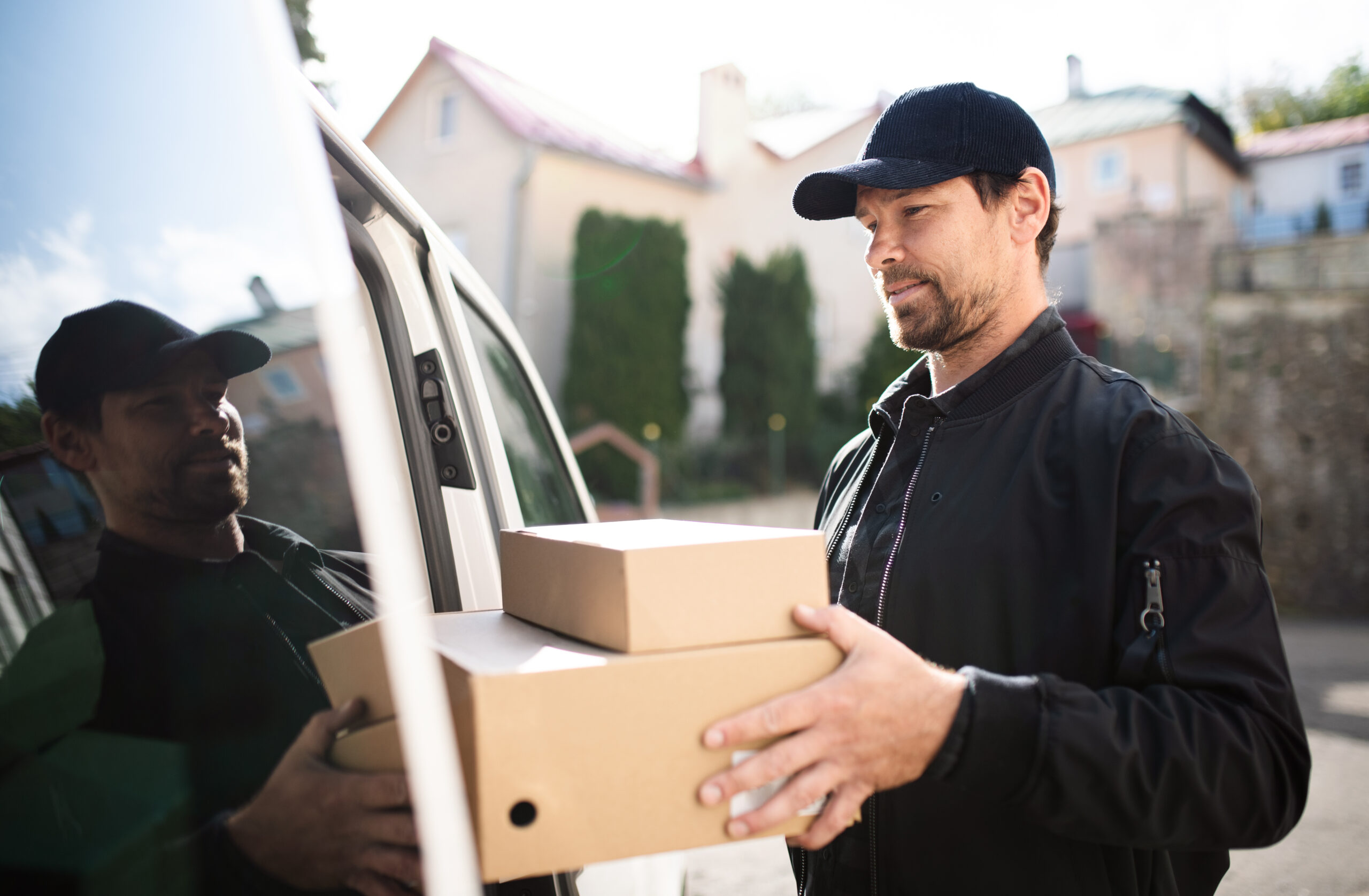 Side view of delivery man courier delivering parcel box in town. Fleetmanagement